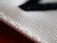A close-up view of a textured fabric material, showcasing the intricate weave of the threads. The white cloth appears to be craft or industrial-grade with a clear focus on its structure, highlighting each individual fiber and strand.
