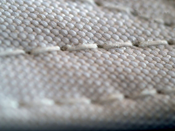 Close-up of layered non-woven fabrics showing texture and lamination process in a textile workshop.