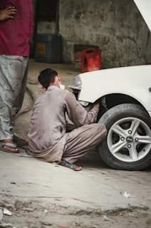 man in gray thobe sitting on white car