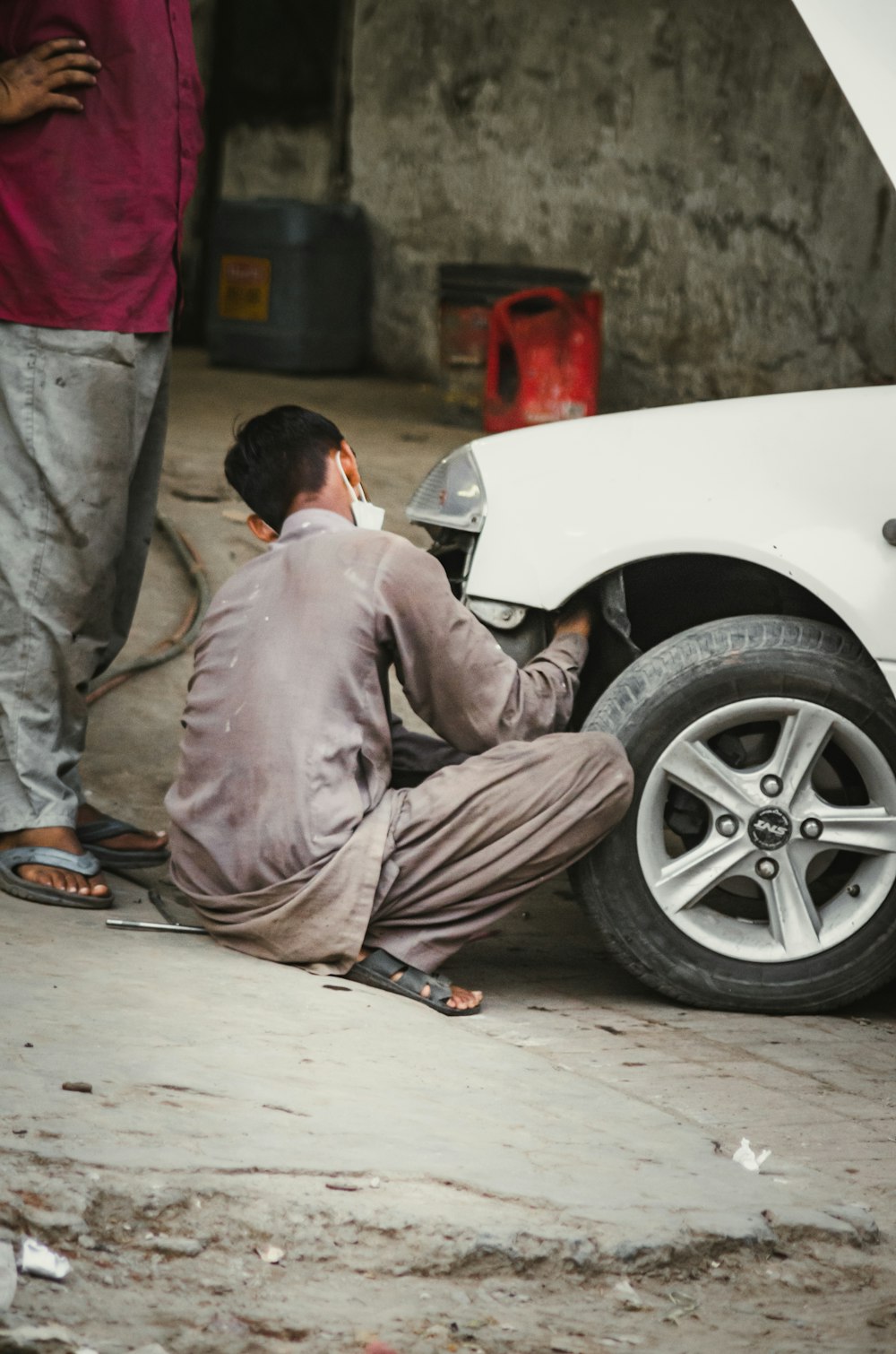 Uomo in thobe grigio che si siede sull'automobile bianca