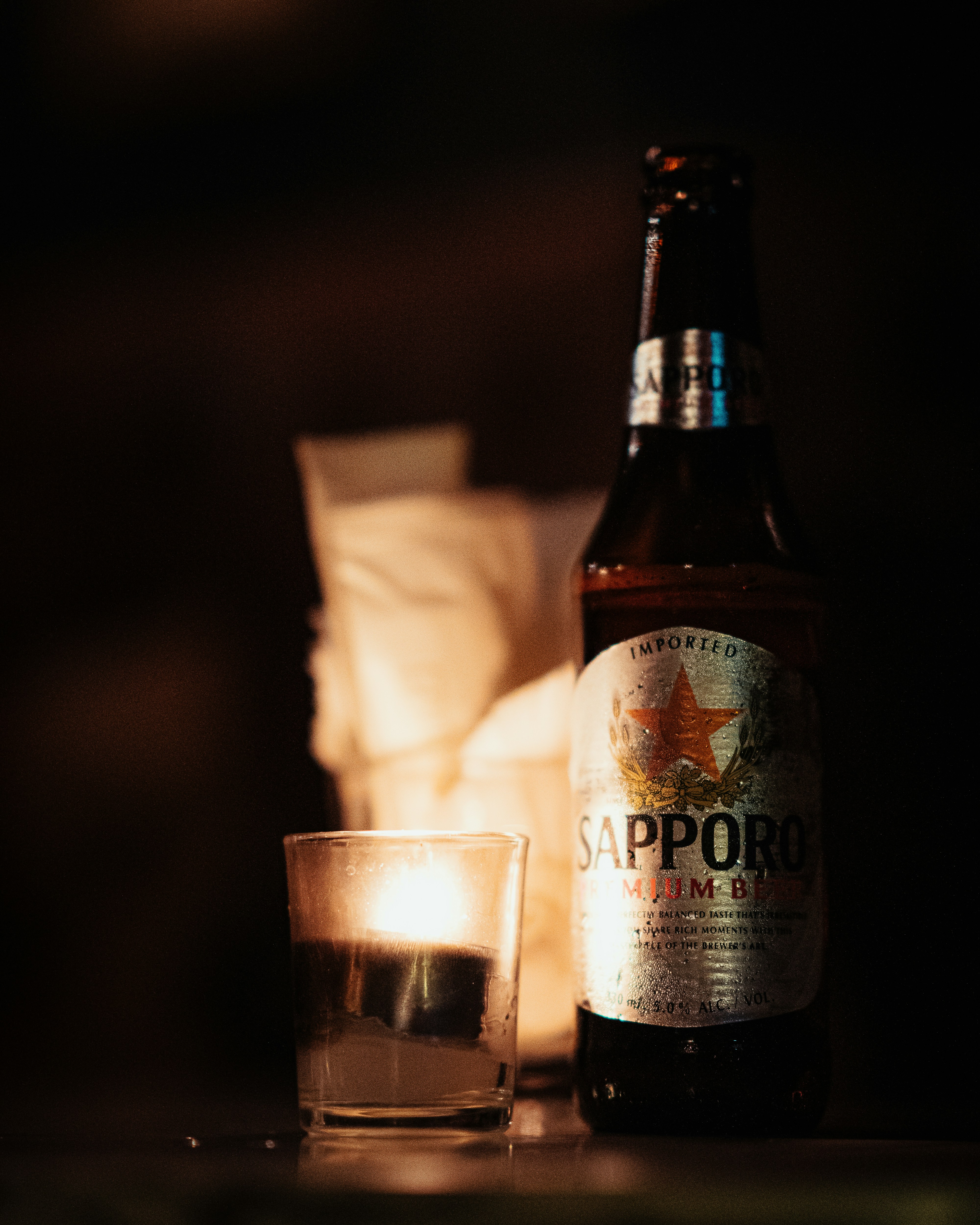 brown glass bottle beside clear drinking glass