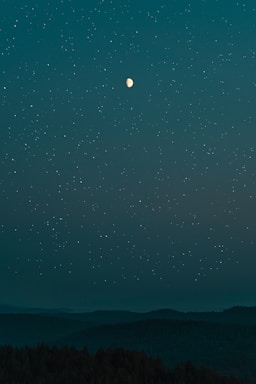 A serene night sky with softly glowing stars and a delicate golden moon illuminating a peaceful landscape.