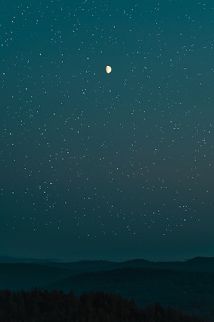 A serene cosmic landscape with stars and a glowing moon illuminating an open spiritual book.