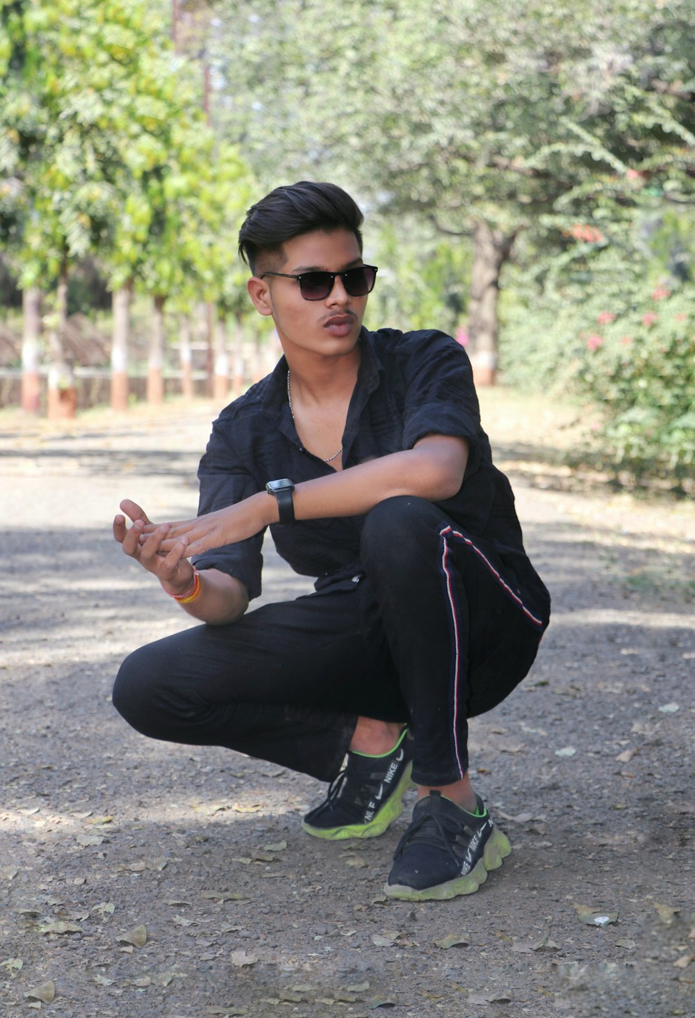 man in black t-shirt and black pants sitting on road during daytime