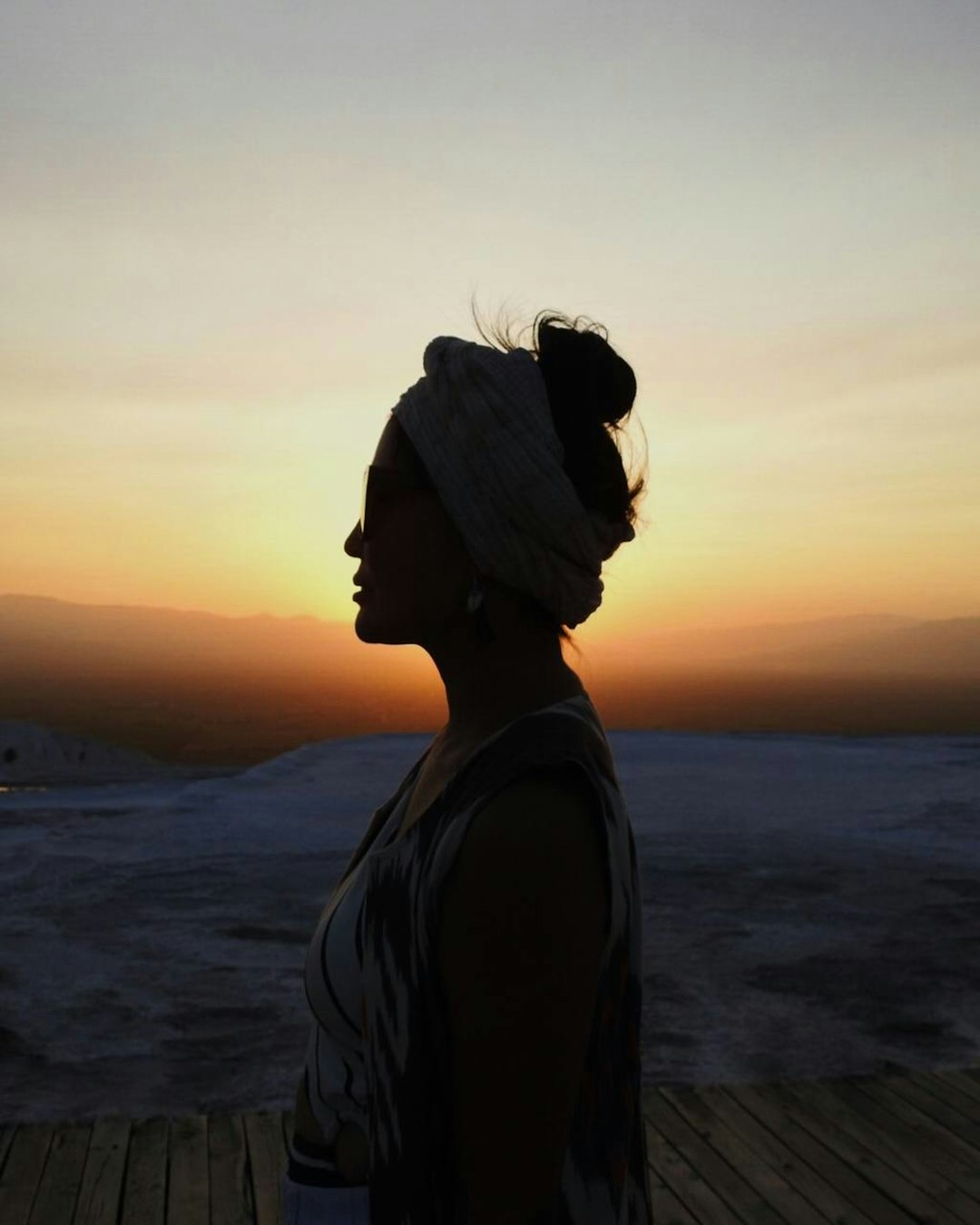 woman in gray shirt standing on beach during sunset