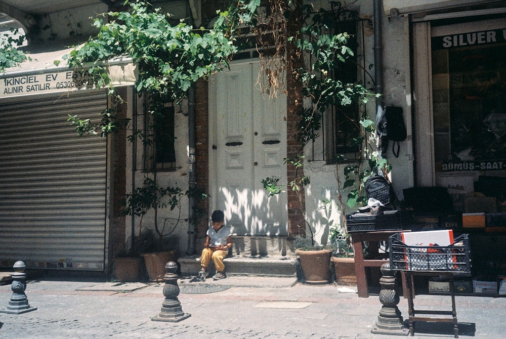 2 boys sitting on bench near white wooden door during daytime