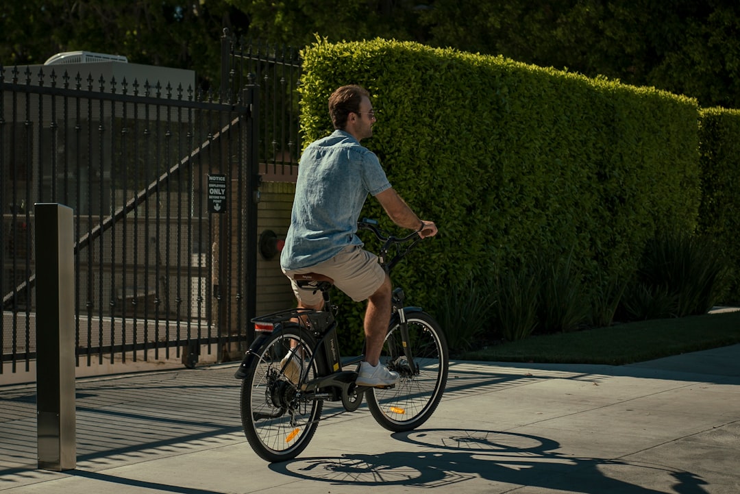 man in blue dress shirt riding on black bicycle during daytime