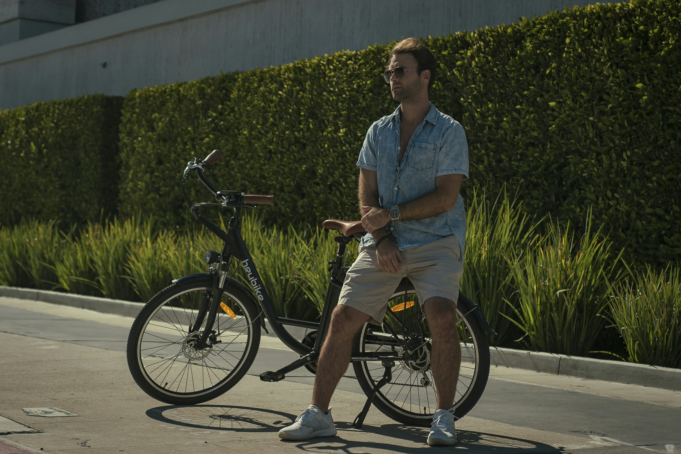 woman in blue button up shirt and brown shorts riding on black bicycle