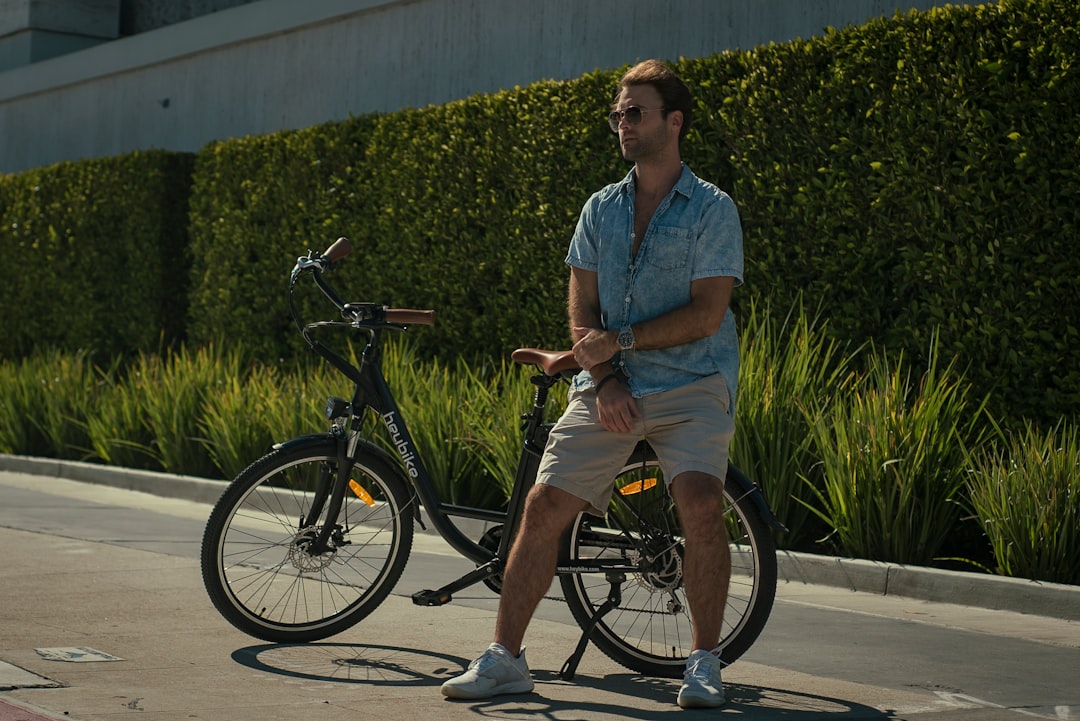 woman in blue button up shirt and brown shorts riding on black bicycle