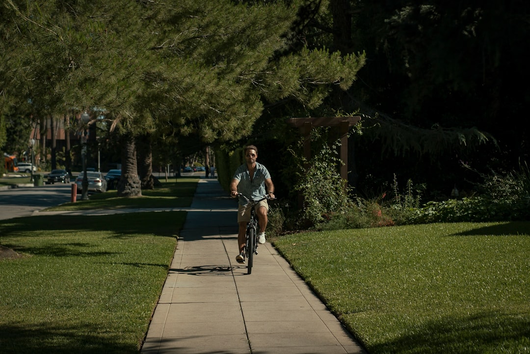 man in black t-shirt riding bicycle on gray concrete pathway during daytime