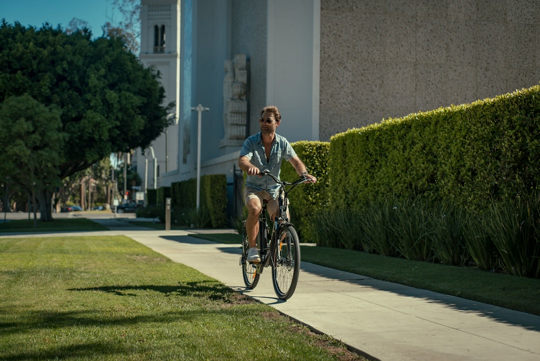 woman in black and white dress riding bicycle on gray concrete road during daytime