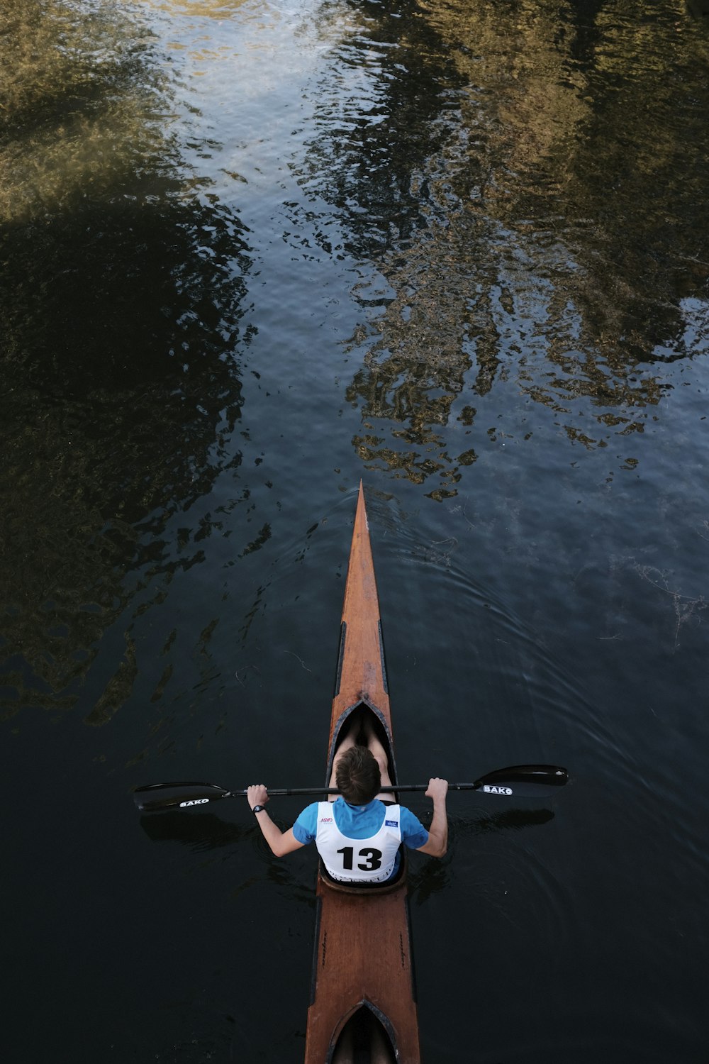 woman in blue and white wetsuit holding orange surfboard on water