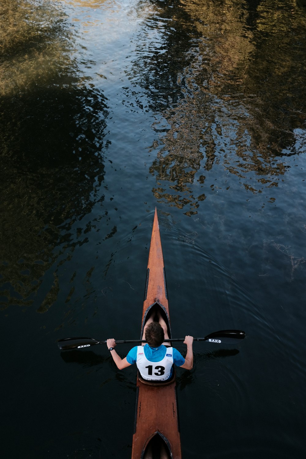 woman in blue and white wetsuit holding orange surfboard on water