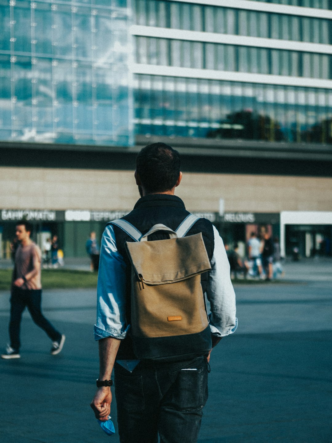 man in white shirt and black backpack walking on street during daytime