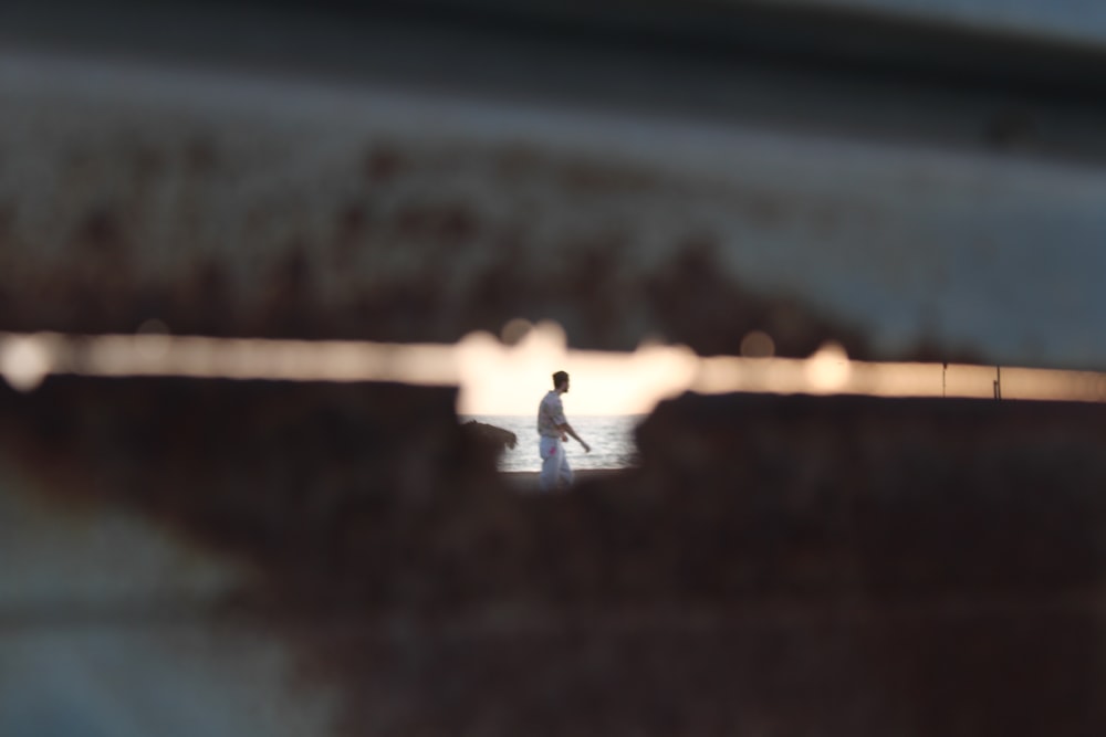 person in white shirt and black pants sitting on brown wooden dock during daytime