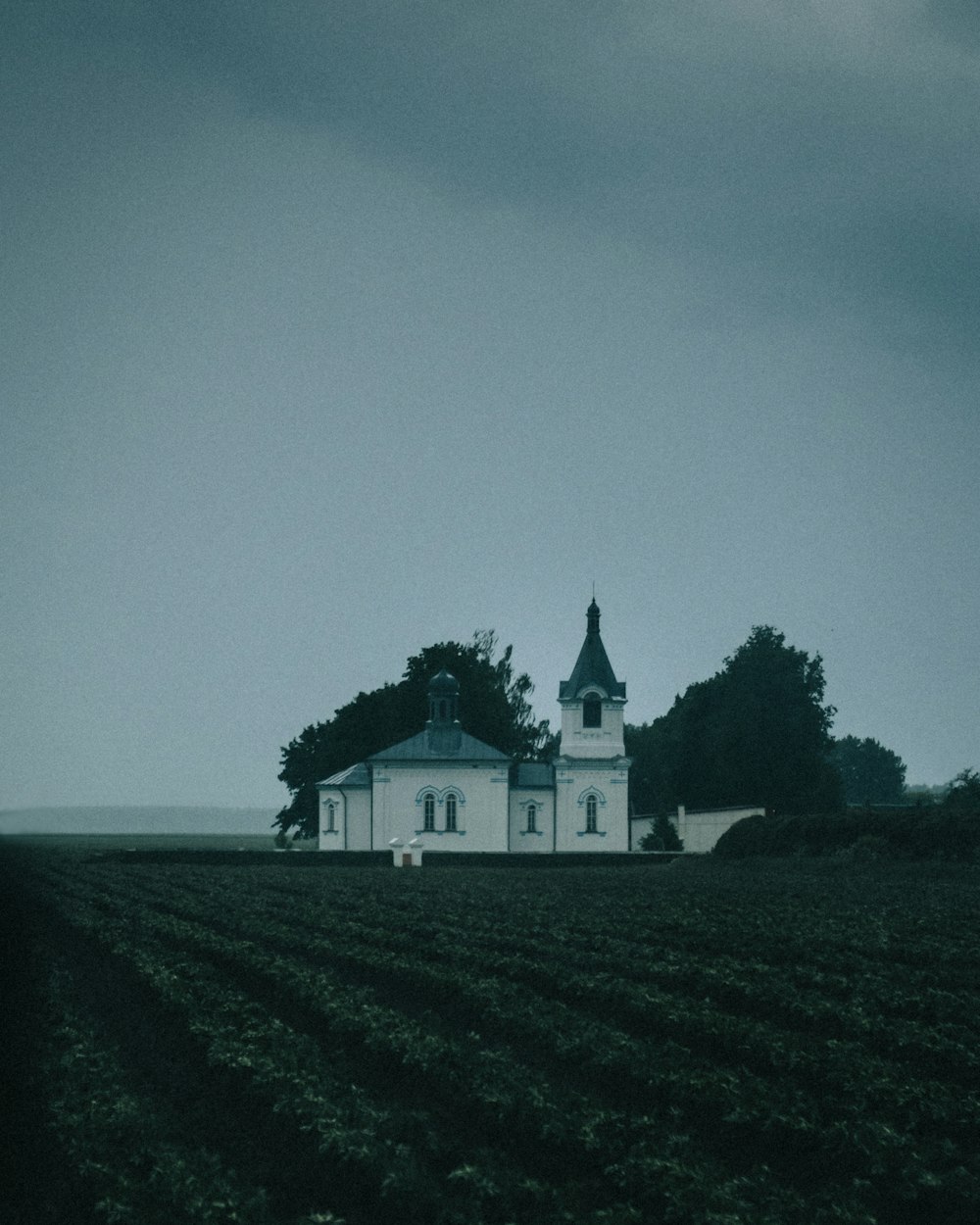 maison blanche et noire sur le champ d’herbe verte sous le ciel gris