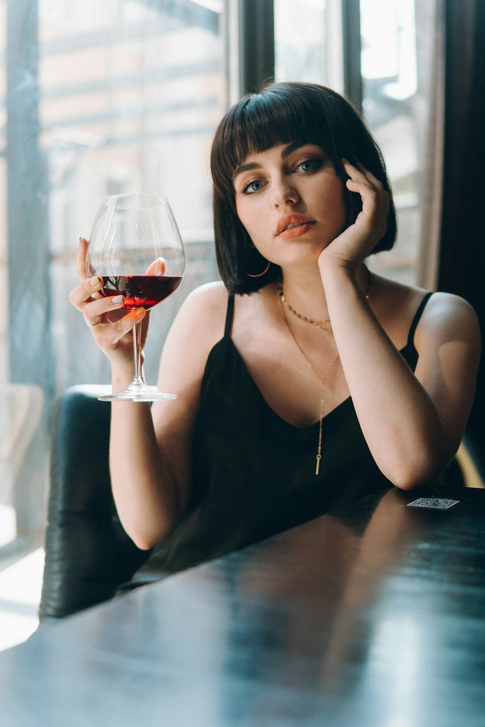 woman in black tank top holding wine glass