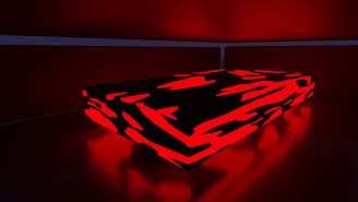 A rectangular, low platform is illuminated with a vivid red and black abstract pattern. The surrounding environment features muted red lighting, creating a dramatic contrast.
