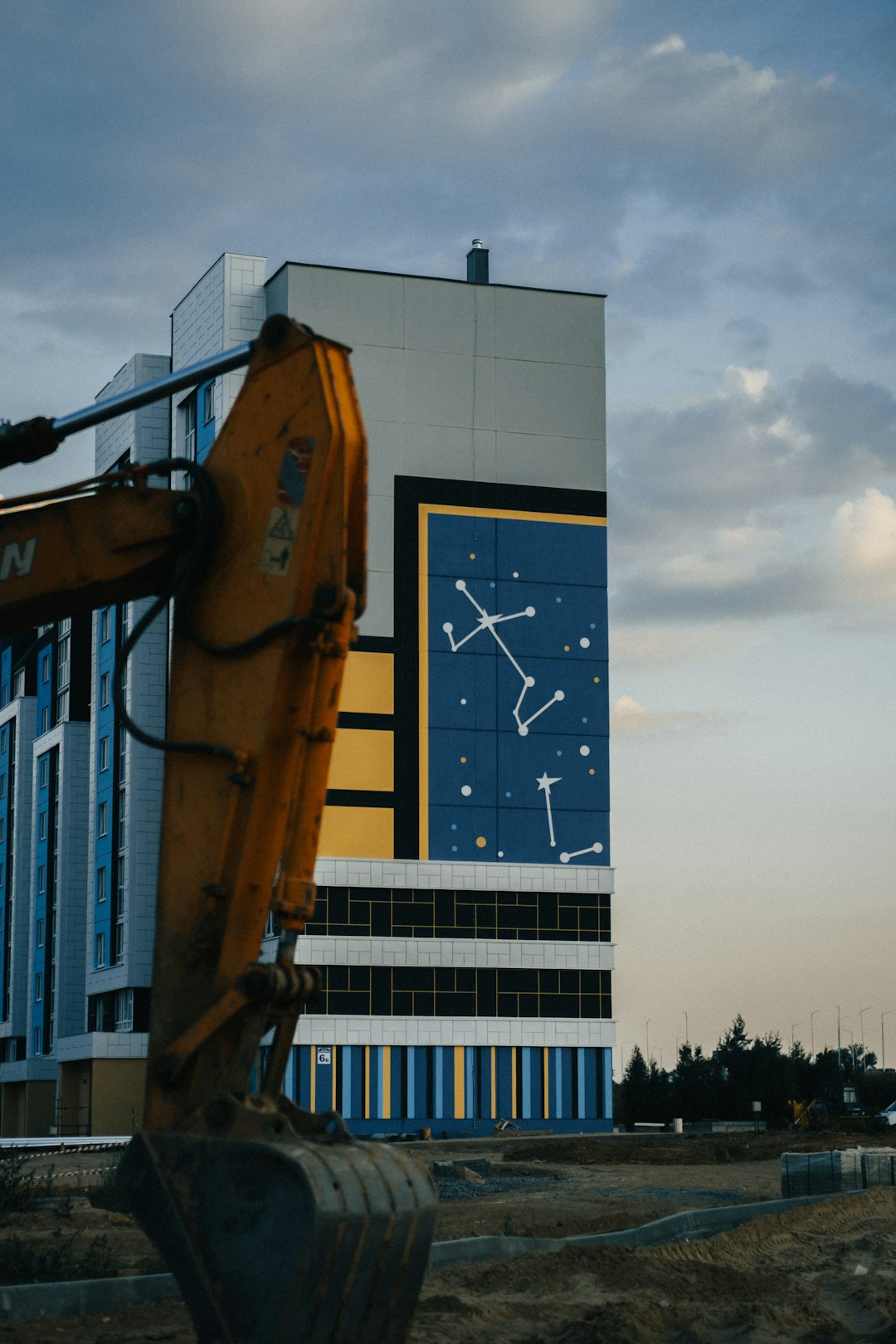 yellow and black crane near blue and white building during daytime