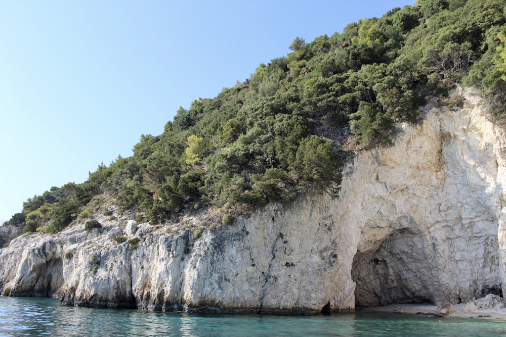 brown and green rock formation beside blue sea under blue sky during daytime