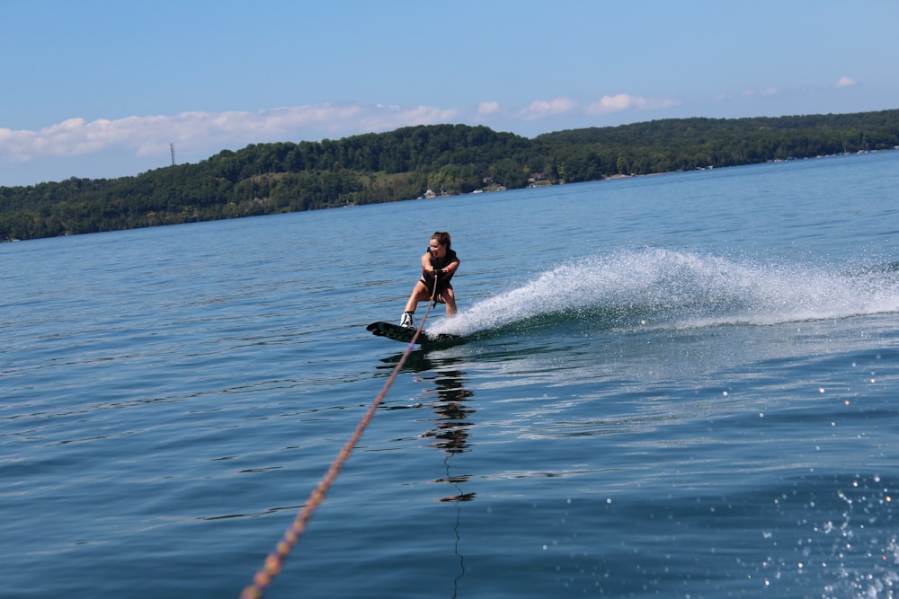 woman in black wetsuit surfing on sea during daytime