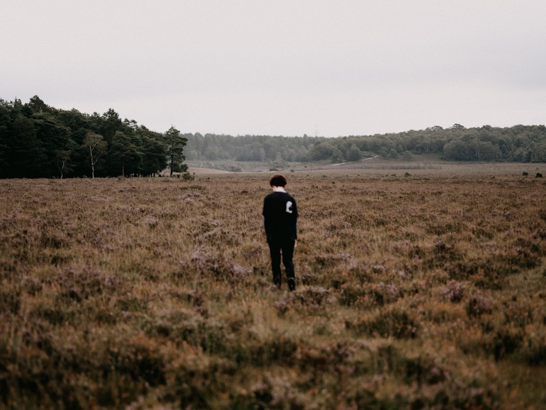 man in black jacket standing on brown grass field during daytime