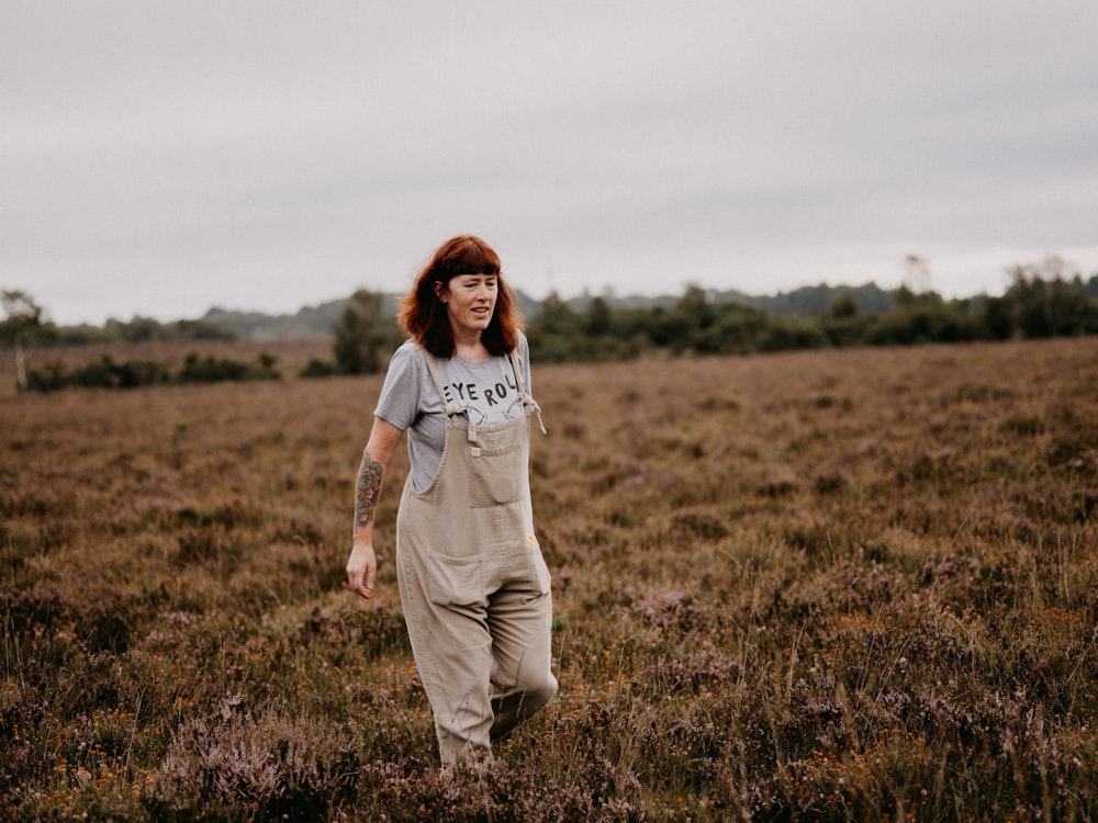 woman in white long sleeve shirt and gray pants standing on green grass field during daytime