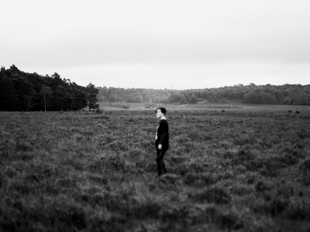 grayscale photo of man walking on grass field