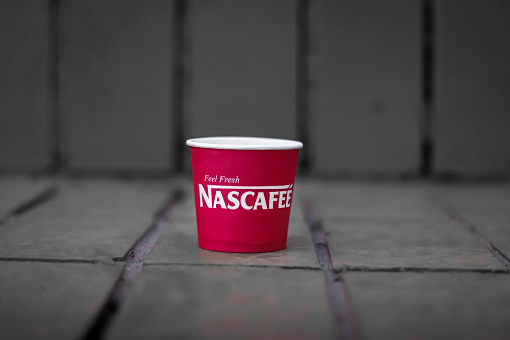 a red cup sitting on top of a tiled floor