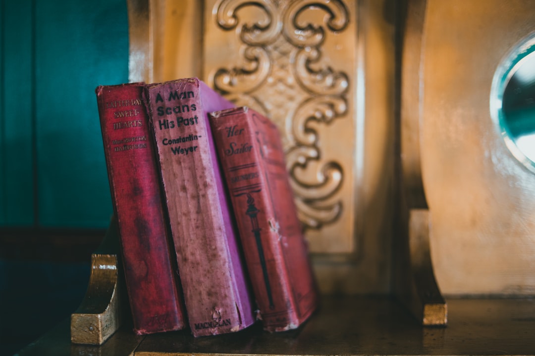 red and purple books on brown wooden shelf