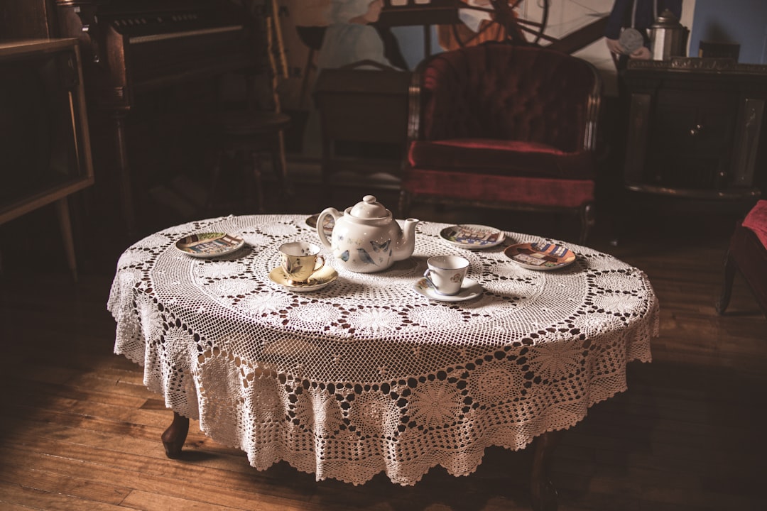white ceramic teacup on white ceramic saucer on white table cloth