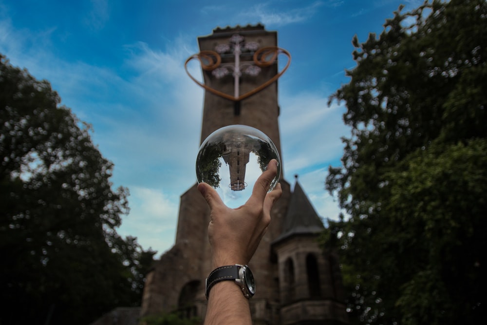 personne tenant une boule de verre transparent