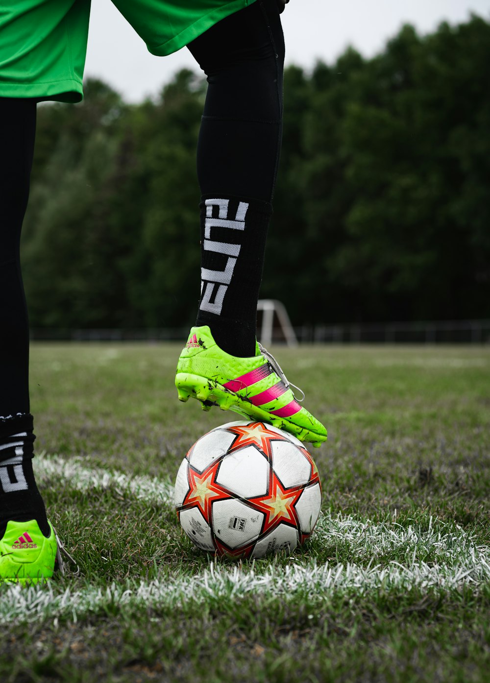 person in green and black soccer jersey kicking soccer ball on green grass field during daytime