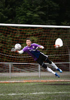 Action shot of a goalkeeper making a spectacular save, diving full stretch to stop the ball.