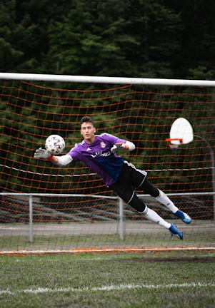A goalkeeper diving to save a ball, framed with futuristic dark and neon blue tones.