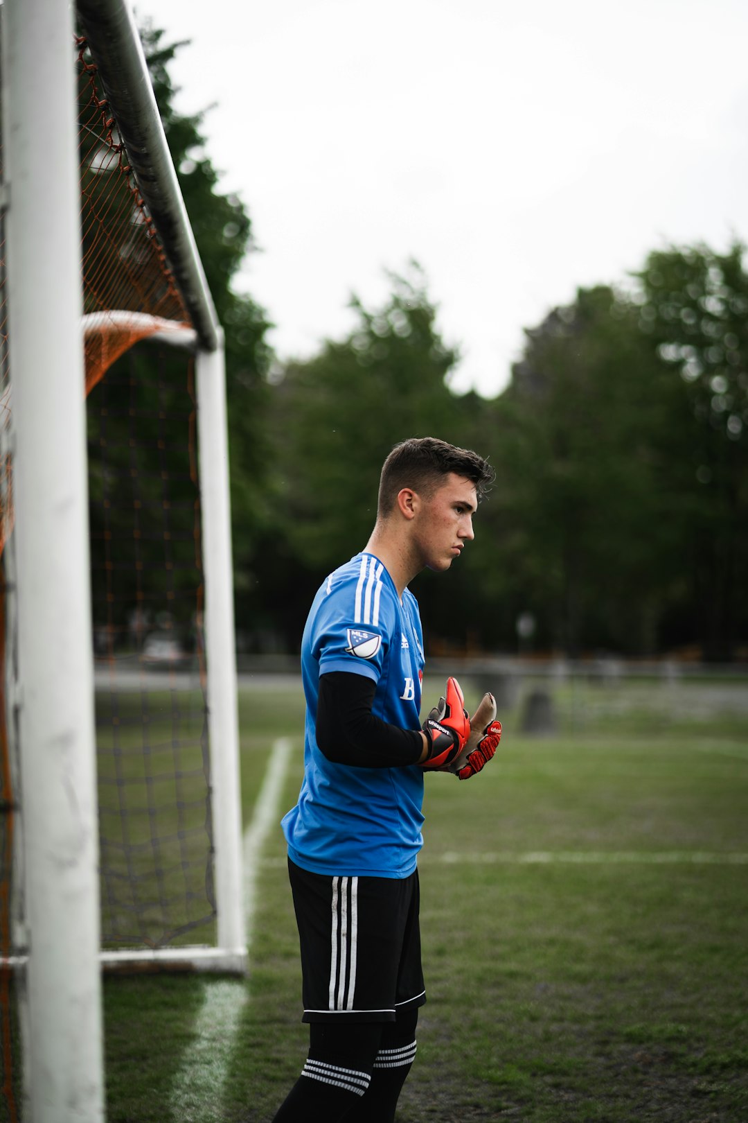 boy in blue and red soccer jersey shirt and black shorts standing on green grass field