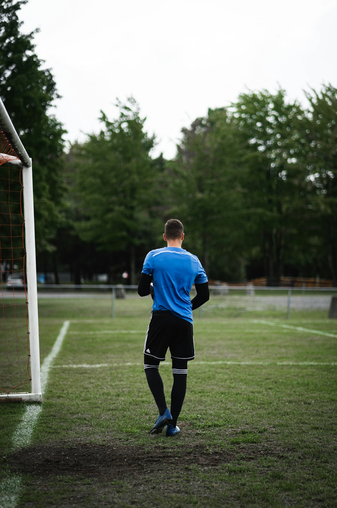 man in blue and white soccer jersey shirt and black shorts standing on green grass field
