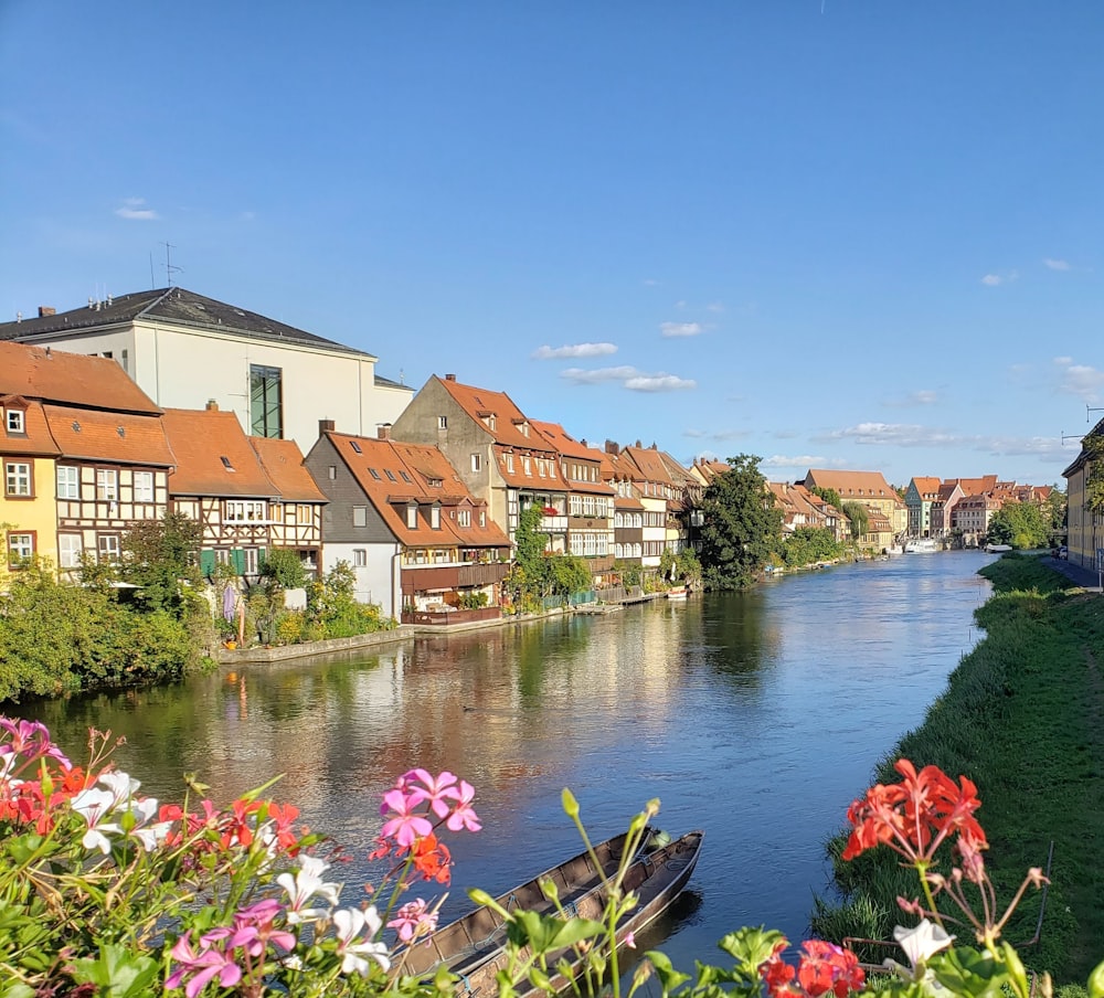 Braune und weiße Betonhäuser am Fluss unter blauem Himmel tagsüber