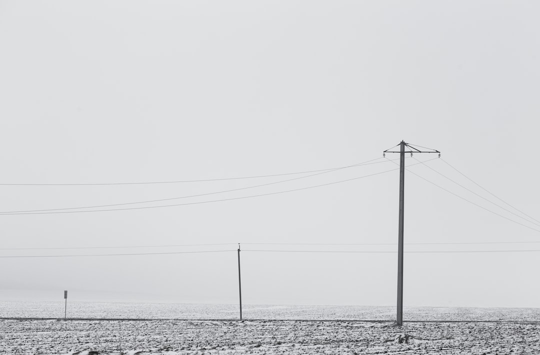 black electric post on snow covered ground under white sky during daytime