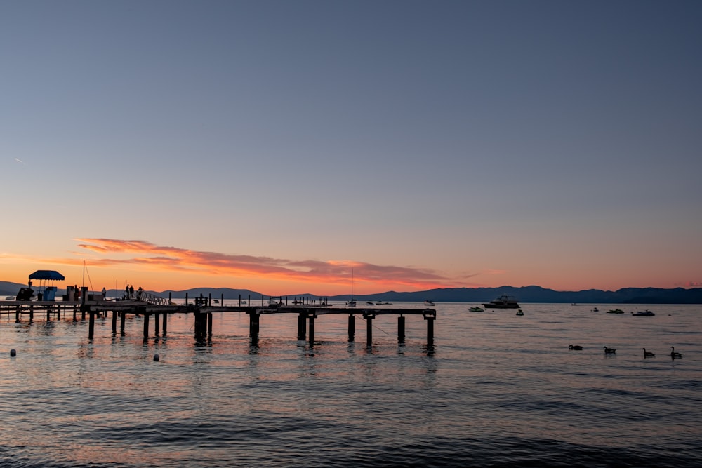 silhouette of dock on sea during sunset