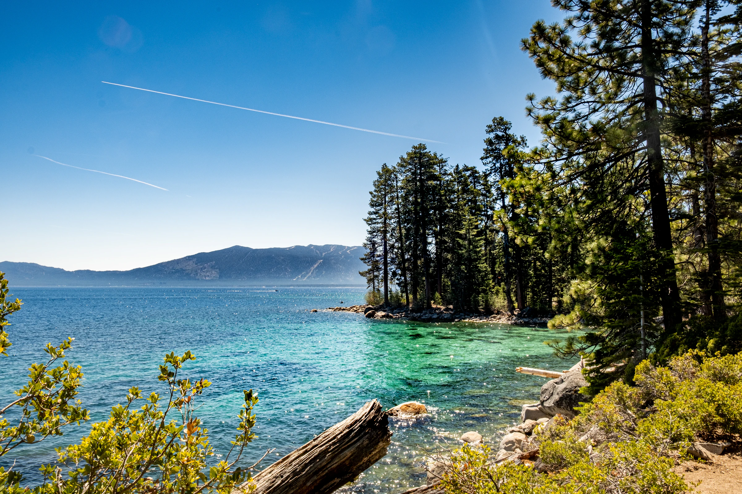 Lake Tahoe emerald cove with pines and mountain backdrop — the Sierra Nevada destination for California buyers relocating to Reno