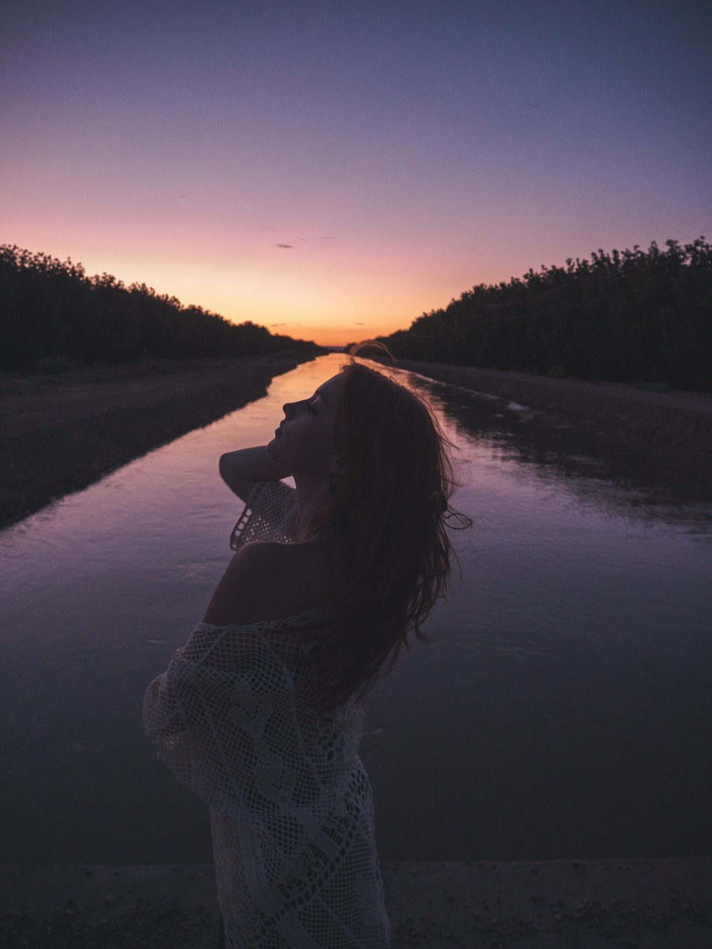 woman in white knit sweater standing on road during sunset