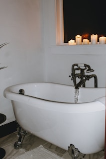 A cozy clawfoot tub surrounded by flickering candles and delicate hanging plants