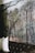 A mural depicting a lush rainforest scene with tall palm trees and dense foliage covers a wall. The corner of a dark leather sofa with tufted detailing is visible in the foreground, along with a couple of white pillows.