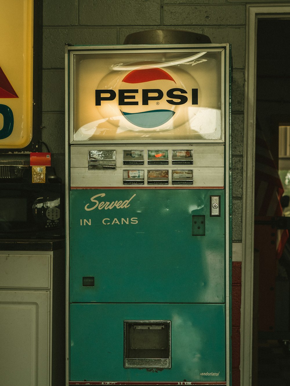 a pepsi machine sitting next to a wall