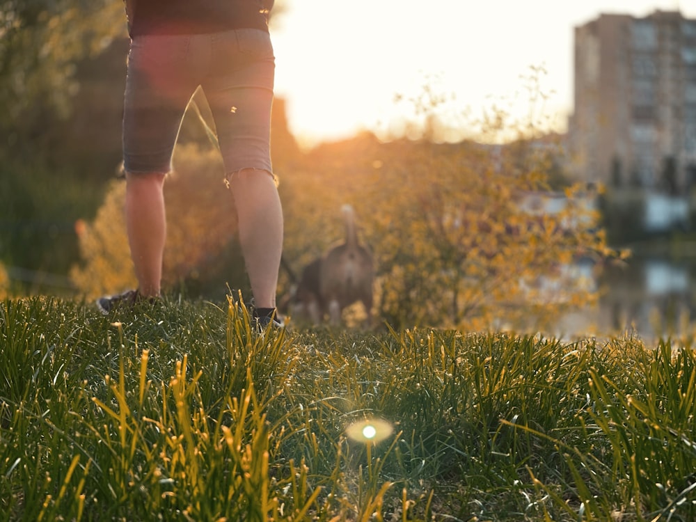 woman in red shirt and blue denim shorts standing on green grass field during daytime