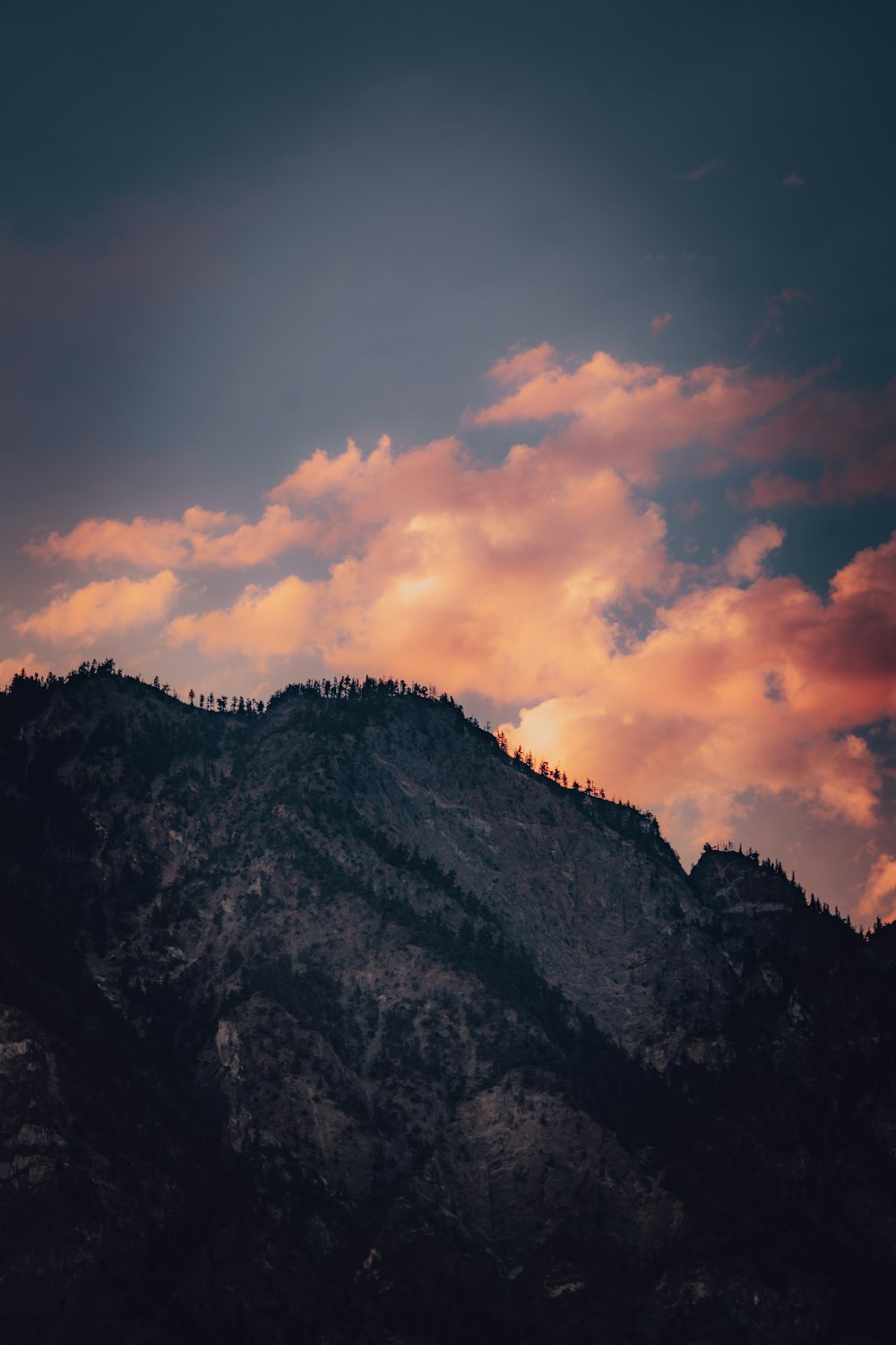 Montaña verde y marrón bajo el cielo nublado durante la puesta del sol