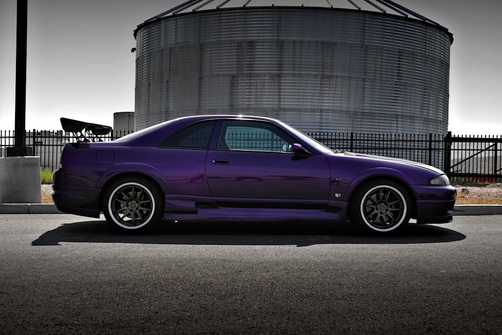 Coupé morado estacionado junto a un edificio gris