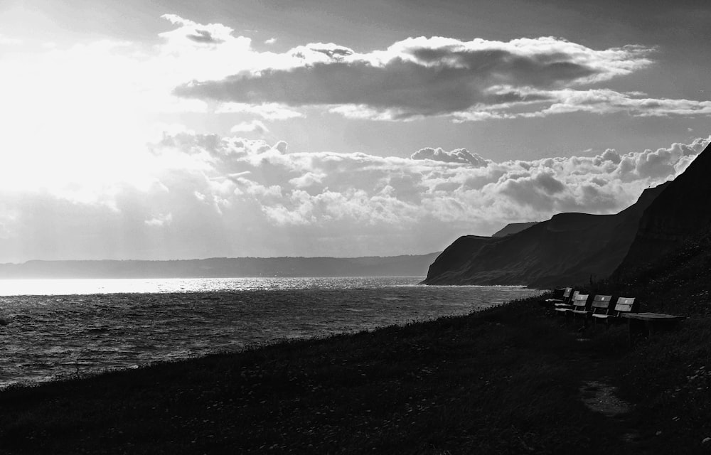 grayscale photo of a person standing on a rock by the sea