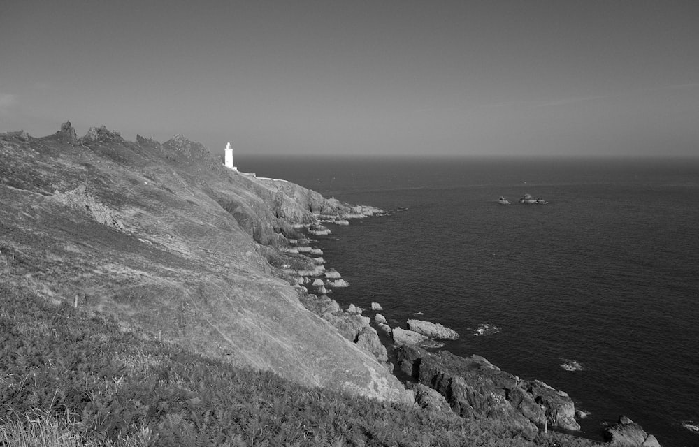 white lighthouse on top of hill near body of water